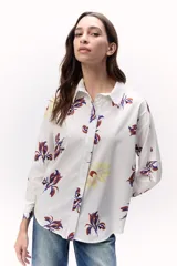 Camisa blanca con estampado floral en tonos amarillo, rojo y azul, de corte recto y manga larga.