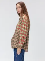 Camisa de manga larga con diseño estampado de rombos en tonos tierra, confeccionada en viscosa. Presenta cuello clásico, cierre frontal con botones, un bolsillo cuadrado en el pecho con logo bordado y puños a juego.