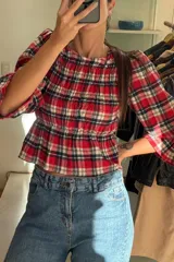 Blusa de viyela color crema con cuerpo fruncido tipo nido de abeja, escote cuadrado y mangas largas abullonadas con puños elásticos.