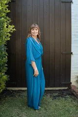 Enterito de mujer color azul piedra, con escote en V, mangas tipo capa y cintura fruncida elástica. El pantalón es de pierna ancha y fluida.