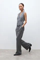 Pantalón sastrero de corte recto y tiro medio, confeccionado en tela con estampado de microcuadros en tonos grises. Presenta bolsillos laterales y cierre frontal con botón.