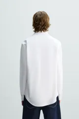 Camisa de corte slim fit con textura, cuello italiano y manga larga con puños abotonados. Presenta cierre frontal con botones.