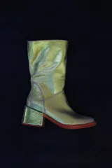 Botas de caña media, color verde iridiscente, con taco cuadrado forrado en cuero y suela roja.