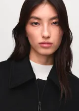 Chaqueta estilo bomber de corte recto y tejido mezcla de lana, con cuello camisero, cierre frontal con cremallera, bolsillos laterales y forro interior.