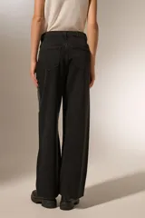 Pantalón de jean negro lavado, tiro alto, corte recto y ancho. Presenta paneles diagonales en la parte delantera de las piernas adornados con tachas metálicas plateadas.