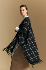 Poncho abierto de tejido de punto con diseño de cuadros grandes en contraste. Presenta un patrón reversible en tonos negro y marrón, con un estilo envolvente y versátil.