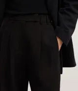 Pantalón de sastrería corte recto confeccionado en crepé, con pliegues delanteros y cintura con detalle cruzado. Presenta un diseño estructurado y elegante.