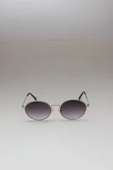 Lentes de sol con montura metálica dorada y cristales ovalados con degradé de gris a transparente.