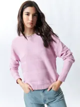 Mochila pequeña color rosa pálido con correas ajustables y asa superior. Tiene un bolsillo frontal con cierre y un parche con el logo de la marca en la parte inferior.