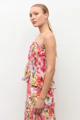 Top de tirantes finos con escote recto y detalle fruncido con elástico en el pecho. Presenta diseño con volados escalonados y estampado floral color rosado.