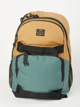 Mochila Rusty modelo Kors, con diseño bicolor en tonos tostado y verde azulado. Cuenta con compartimento principal con cierre, bolsillo frontal con cierre, correas ajustables negras y bolsillos laterales de red.