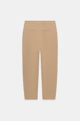 Pantalón de tiro medio con pinzas delanteras, bolsillos laterales y falsos bolsillos de vivo en la parte trasera. Presenta un corte holgado que se estrecha hacia el tobillo, con bajo acabado en pliegues y cierre frontal con cremallera, botón interior y gancho.
