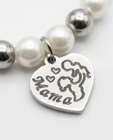 Pulsera elástica compuesta por una combinación de perlas blancas y esferas metálicas plateadas, con un dije colgante en forma de corazón con grabado.