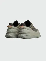 Zapatillas de trail running Moncler modelo Trailgrip GTX, color verde oliva y marrón topo. Presentan un sistema de cordones elásticos con tope, puntera y suela robusta con tacos prominentes para tracción.