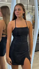 Vestido corto azul marino con brillos, escote recto, tirantes finos cruzados en la espalda y falda cruzada con tajo lateral.