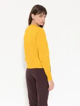 Sweater color crema de cuello redondo y corte regular, largo hasta la primera cadera.