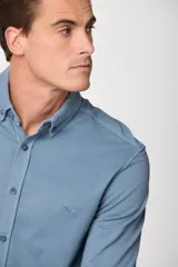 Camisa de manga larga color azul, con cuello abotonado y logo bordado en el pecho.