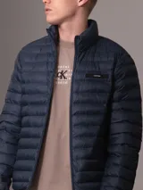 Campera inflada Calvin Klein color azul marino, con cuello alto, cierre frontal con cremallera, bolsillos laterales y logo de la marca en el pecho.