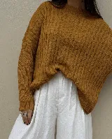 Sweater de punto color mostaza con diseño de trenzas verticales en la parte frontal, cuello redondo y mangas largas con puños acanalados.