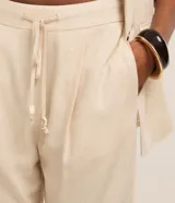 Pantalón fluido Marfinno modelo pijama, color blanco, confeccionado en viscolino. Cuenta con cintura elástica en la espalda, lazo de ajuste, pliegues frontales y bolsillos laterales.