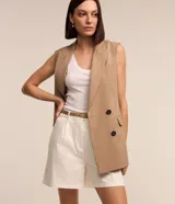 Short de sastrería color beige, de corte recto con pinzas delanteras y trabillas en la cintura. Incluye un cinturón de poliuretano a tono con hebilla metálica dorada.