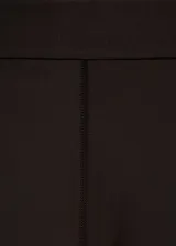 Pantalón slim fit de color marrón oscuro, con diseño largo, cintura elástica y detalle de costuras. Presenta una abertura en el bajo con cierre de cremallera.