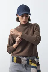 Polera de tejido de punto color gris oscuro, con cuello alto y diseño de rombos en relieve en el frente. Presenta un calce relajado con terminaciones en rib en cuello, puños y ruedo.