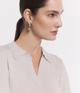 Blusa de punto ajustada color negro, con cuello polo y escote pronunciado en V. Presenta un tejido acanalado vertical en el torso y mangas largas.