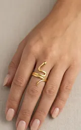 Anillo de acero dorado con diseño en forma de serpiente enrollada alrededor del dedo.