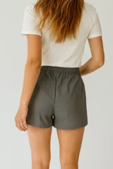 Short negro de poliéster, de calce holgado y tiro medio, con cintura elástica y cordón ajustable.