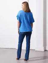 Blusa de mujer color azul vibrante con textura acanalada y pequeños patrones jacquard en relieve. Presenta un escote redondo y mangas cortas con vuelo.