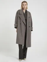 Tapado largo de paño texturado color gris topo, de corte oversize y doble botonadura. Presenta cuello con solapas anchas y mangas largas con puños doblados.