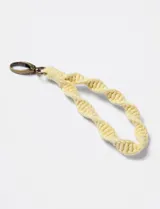 Llavero amarillo tejido con diseño de doble espiral y gancho metálico color bronce.