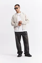 Campera tipo bomber color beige, con cierre frontal completo, cuello redondo y puños elásticos. Presenta una textura sutil en la tela y un calce cómodo.