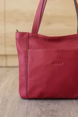 Cartera tipo tote de cuero vacuno negro con doble asa de hombro, panel superior liso y bolsillo exterior frontal con textura símil cocodrilo y costuras visibles en contraste.