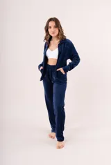 Conjunto de dos piezas confeccionado en tela plush, compuesto por una campera con cierre frontal y cuello alto, y un pantalón de corte recto. Presenta un diseño minimalista y cómodo en color gris claro.