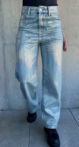 Pantalón de jean celeste con estampado de cuadrados plateados reflectantes.