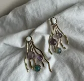 Aros colgantes de alpaca plateada con diseño de ramitas y piedras de colores: blanco, lila y verde.