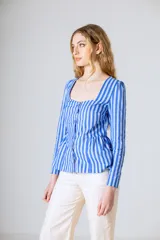 Blusa de manga larga con estampado de rayas verticales en tonos azul y blanco. Presenta un escote cuadrado, cierre frontal con botones y un diseño con corte peplum en la cintura.