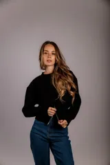 Suéter de punto color crema, con cuello redondo, manga larga y cierre frontal parcial que deja ver parte del abdomen.