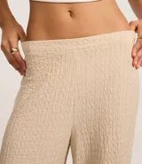 Pantalón texturizado marrón de corte ancho con cintura elástica y bolsillos laterales.