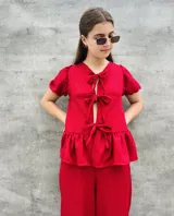 Blusa estampada con hojas verdes y blancas, con escote en V y mangas cortas abullonadas. Presenta volados en el ruedo y detalle de lazos en el frente.