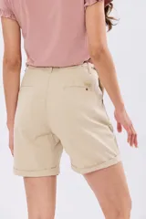 Bermuda de lino clásica color beige, de corte recto y tiro alto, con bolsillos laterales y vuelta en el ruedo. Incluye un cinto trenzado claro con detalles en marrón y hebilla metálica dorada.