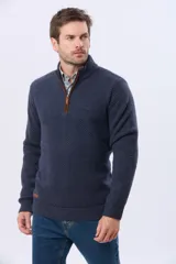 Buzo tejido de punto grueso en color azul marino, con cuello alto y cierre frontal parcial. Presenta detalles en gamuza en la zona del cierre y una textura en relieve en toda la prenda.