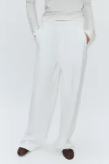 Pantalón de tiro alto confeccionado en tejido fluido, con diseño de pierna recta y holgada. Presenta pliegues frontales, trabillas para cinturón, bolsillos laterales y bolsillos de vivo en la parte posterior. Cierre frontal con botón.