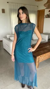 Vestido largo de microtul bordó, sin mangas, con escote alto tipo buche y diseño transparente con forro corto interno que genera un efecto translúcido en la falda.