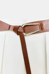 Falda midi color blanco, de tiro alto, con cinturón marrón ancho y pinzas delanteras. Tiene corte evasé y cierre trasero con cremallera oculta.