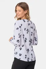 Blusa blanca con estampado de lunares negros, de manga larga y cuello redondo con abertura en la espalda.