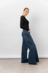 Jean de tiro alto con corte wide leg y pierna amplia. Confeccionado en denim rígido de lavado azul clásico, cuenta con bolsillos funcionales y cierre frontal.