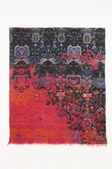 Pashmina rectangular con diseño bicolor, presentando un lado con estampado paisley en tonos oscuros y otro lado en color fucsia vibrante con textura tejida. Posee terminaciones desflecadas en los extremos.